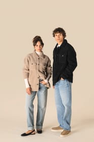 Surchemises en sherpa beige et noire portées par un homme et une femme