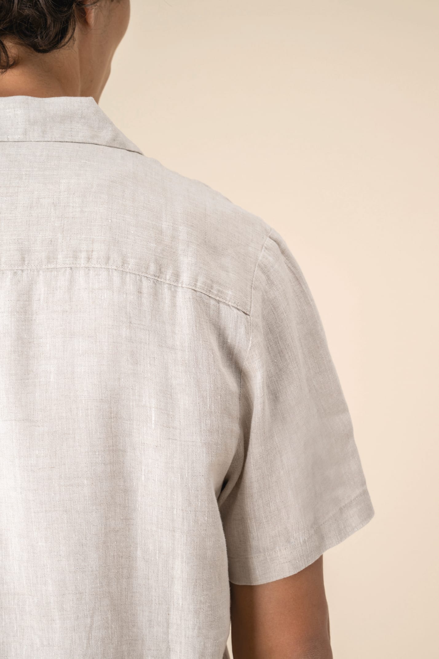 Détail épaule chemise à manches courtes en lin beige portée par un homme