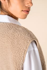 Détail épaule d'un veste sans manches en sherpa beige portée par une femme