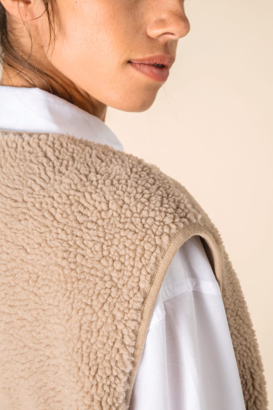 Détail épaule d'un veste sans manches en sherpa beige portée par une femme