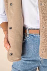 Détail des boutons d'un veste sans manches en sherpa beige portée par une femme