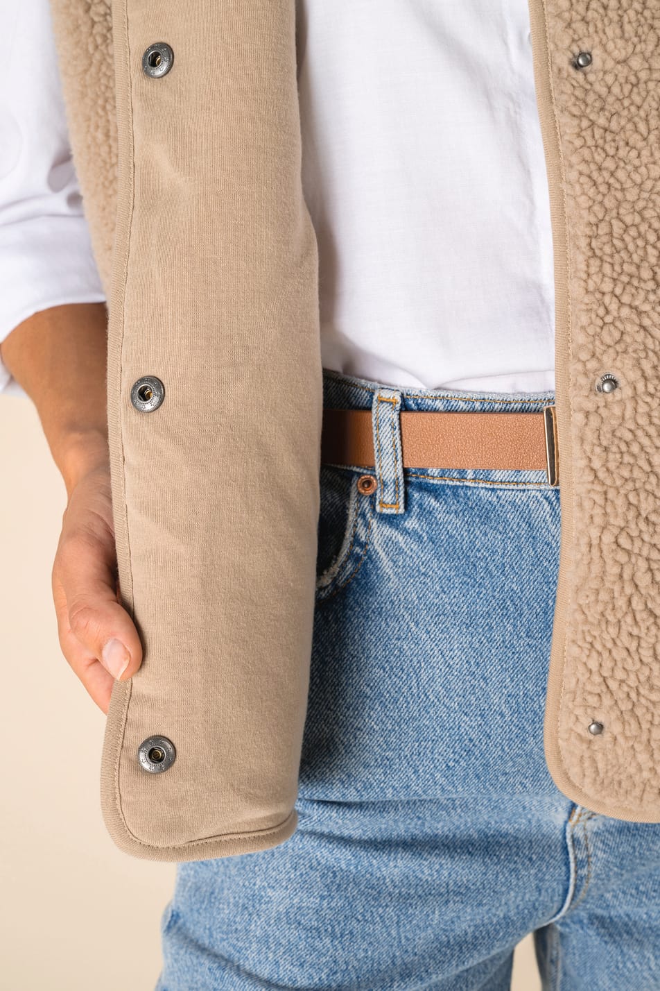 Détail des boutons d'un veste sans manches en sherpa beige portée par une femme