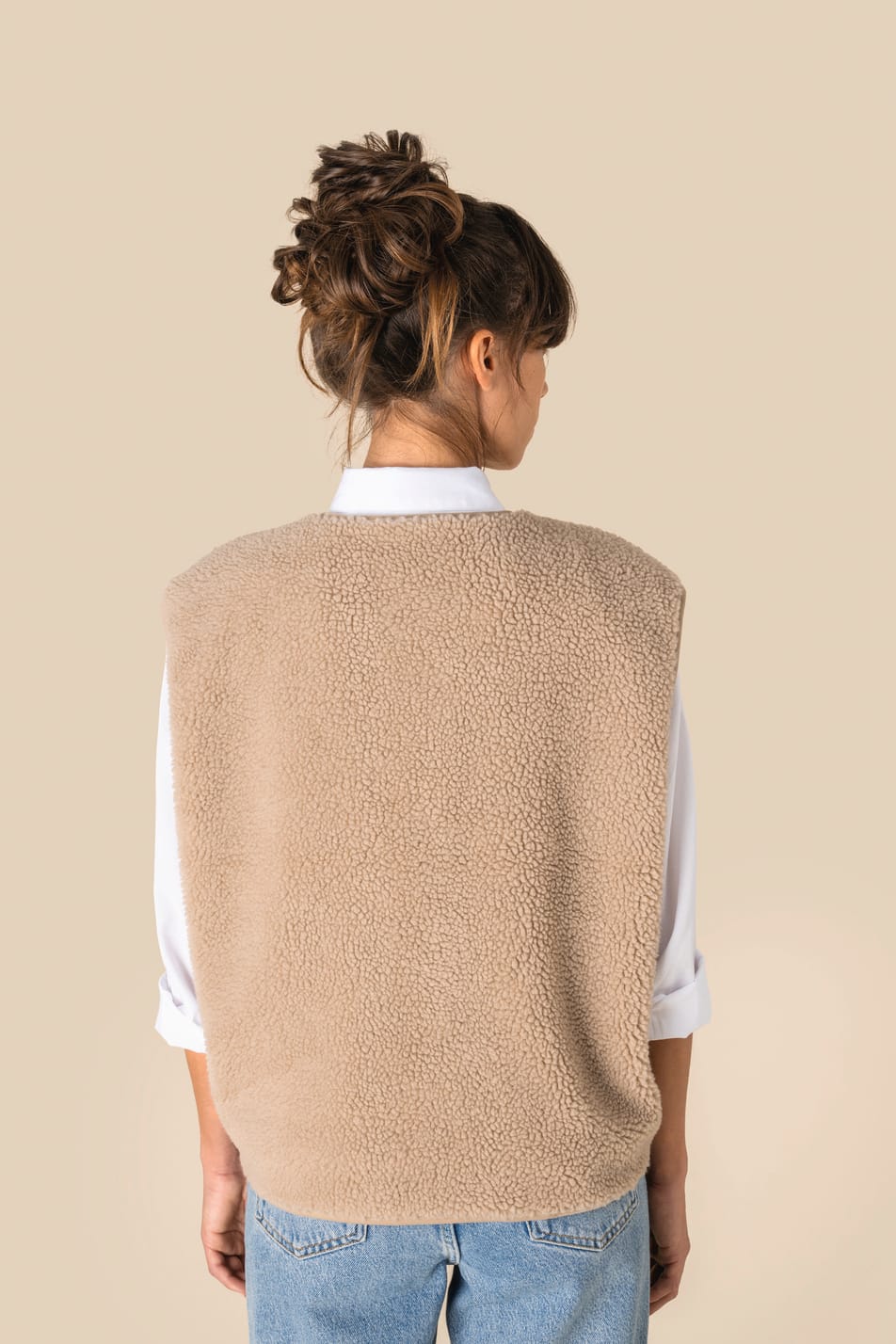 Veste sans manches en sherpa beige portée par une femme de dos