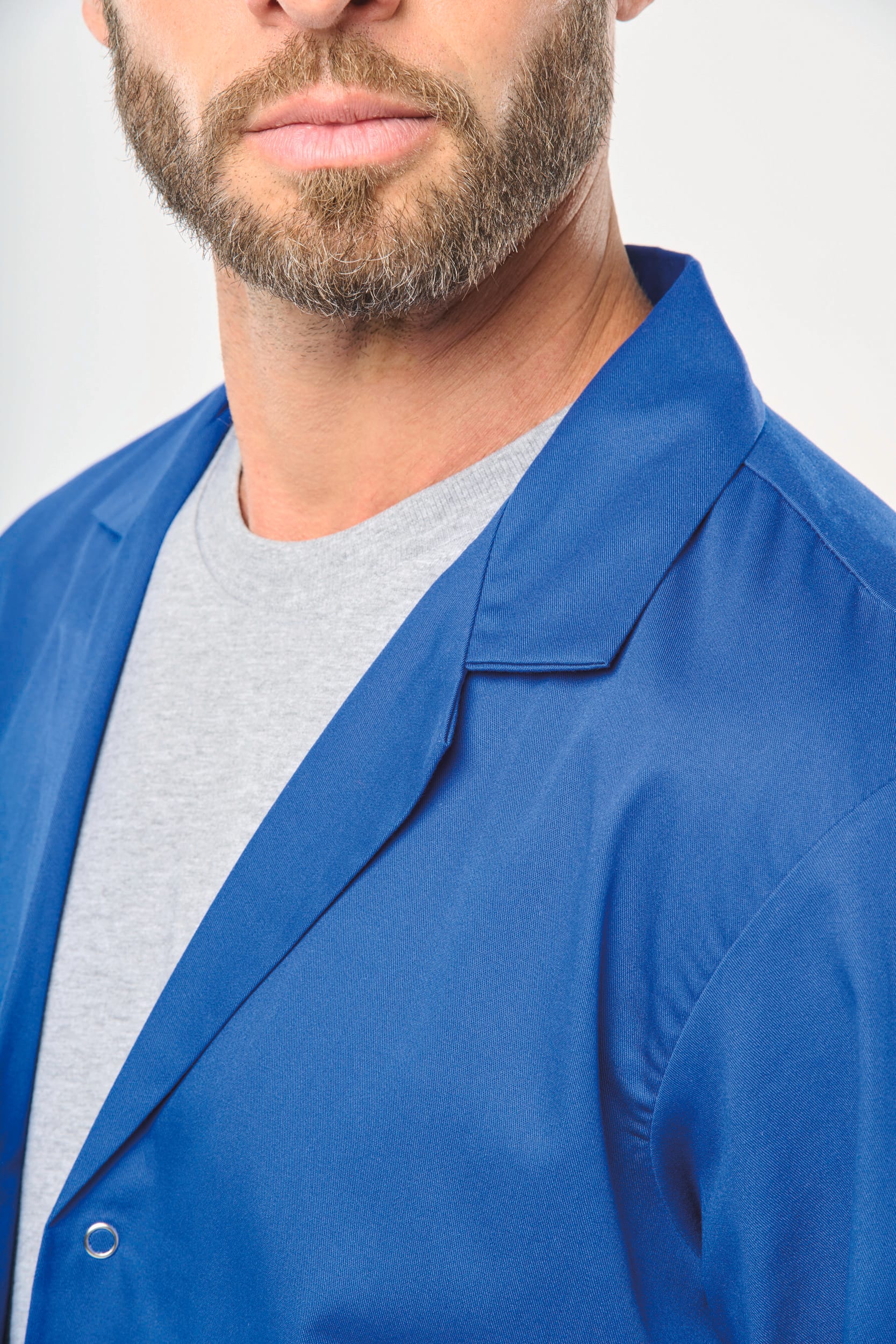 Détail col de la blouse en couleur bleu porté par un homme.