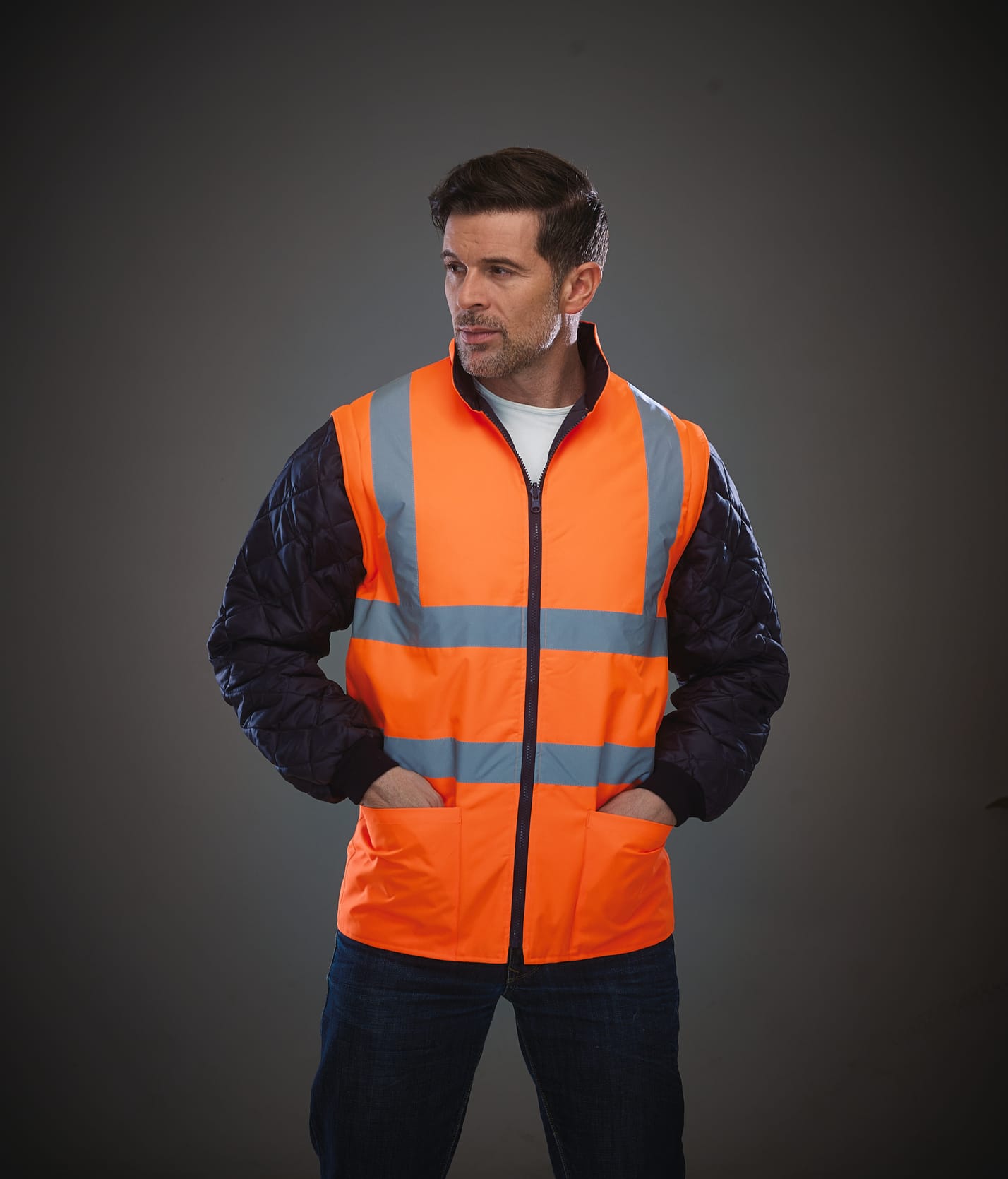gilet de sécurité sans manches orange fluo avec bandes réfléchissantes porté par un homme avec les pains dans les poches