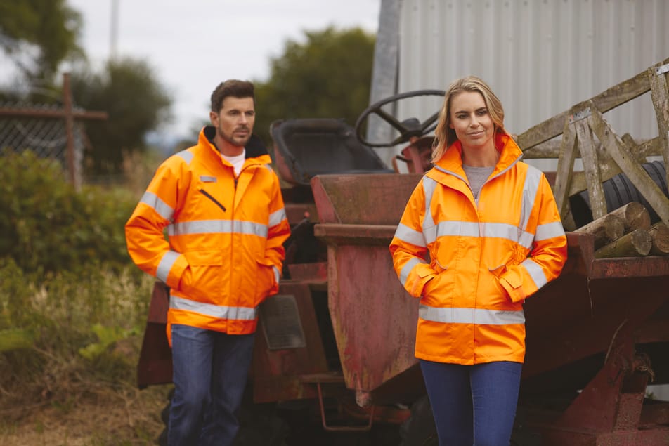 veste orange fluo haute visibilité avec bandes réfléchissantes fullzip multipoches col montant portée par un homme et une femme