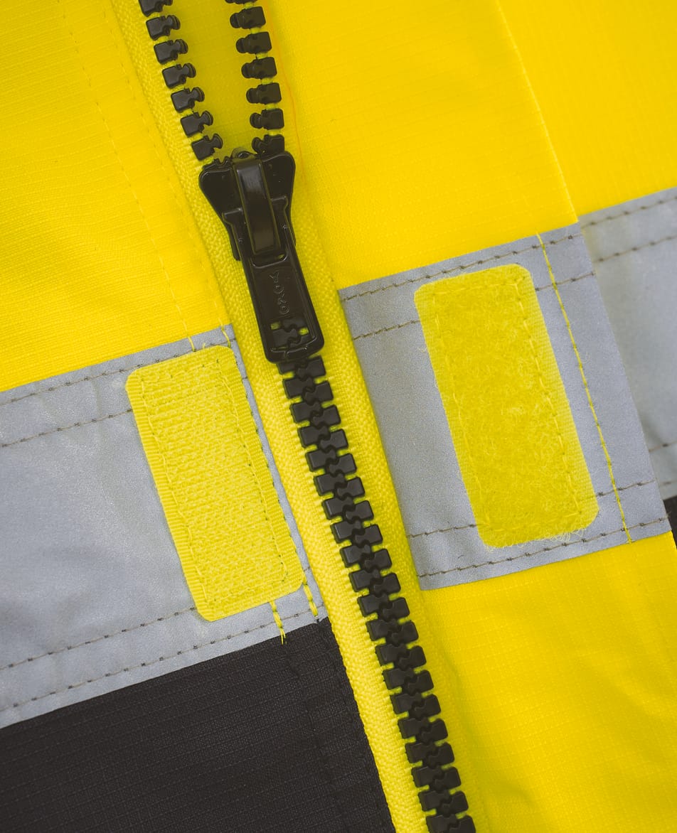 zoom sur détail zip sur veste bicolore jaune fluo et bleu foncé avec bandes réfléchissantes