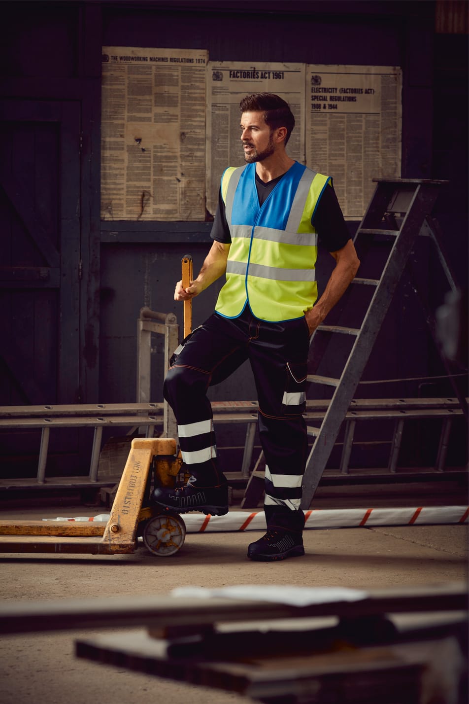 gilet bicolore bleu royal et jaune fluo haute visibilité avec bandes réfléchissantes sans manches fermeture velcro porté par un homme debout