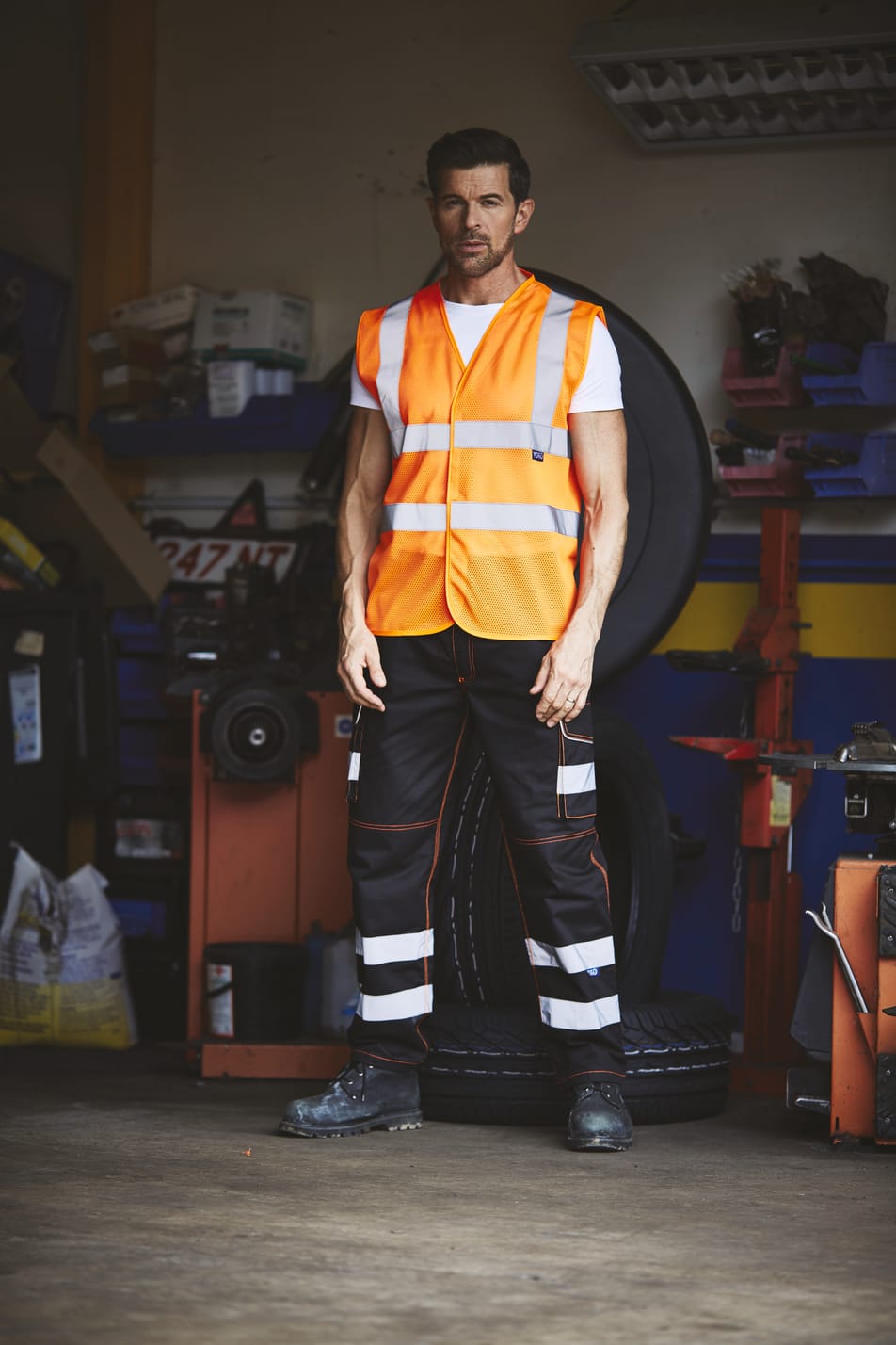 gilet orange fluo haute visibilité avec bandes réfléchissantes sans manches fermeture velcro porté par un homme debout