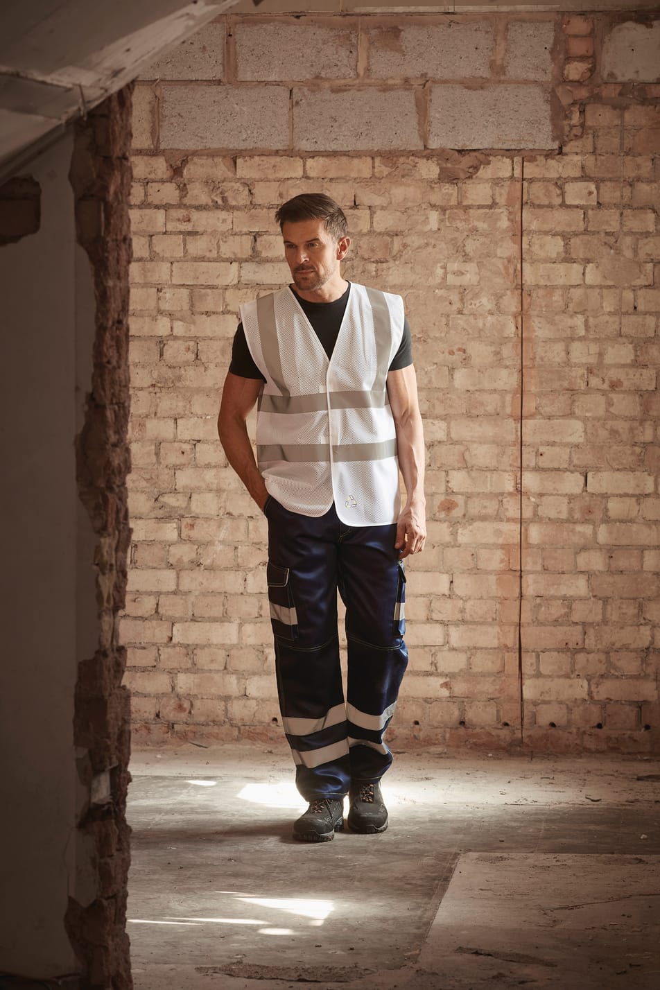 gilet sans manches blanc avec bandes réfléchissantes haute visibilité porté par un homme avec un pantalon bleu